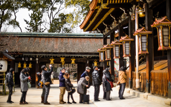 desktop background image of people lined up to pay respects at the Kitano Tenmangu Shrine (北野天満宮), Kyoto Japan -- Queue -- Kitano Tenmangu Shrine (北野天満宮) -- Copyright 2013 Jeffrey Friedl, http://regex.info/blog/ -- This photo is licensed to the public under the Creative Commons Attribution-NonCommercial 4.0 International License http://creativecommons.org/licenses/by-nc/4.0/ (non-commercial use is freely allowed if proper attribution is given, including a link back to this page on http://regex.info/ when used online)