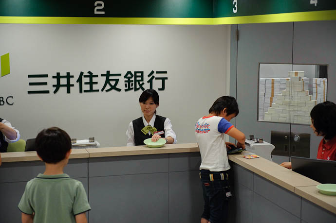 Finally His Turn teller presents dish for the customer to place paperwork or whatnot -- KidZania Koshien -- Kyoto, Japan -- Copyright 2009 Jeffrey Friedl, http://regex.info/blog/